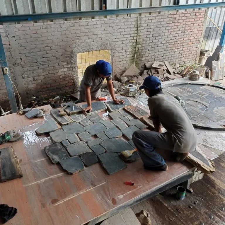 Indonesian artisans using specialized tools to process petrified wood in a workshop