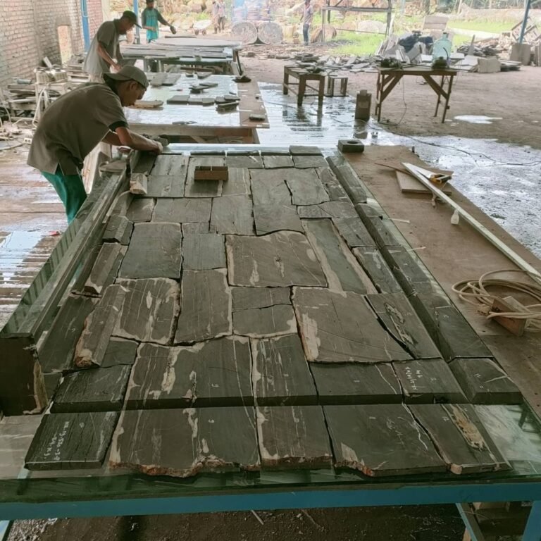 Skilled artisan working on a high-end petrified wood slab in an Indonesian stone processing workshop