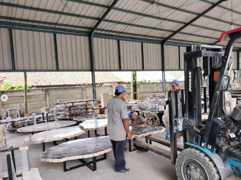 A skilled Indonesian worker using professional tools to polish a natural petrified wood slab in a manufacturing facility.